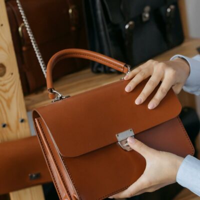 A stylish leather handbag being presented in a sleek, modern showroom setting.