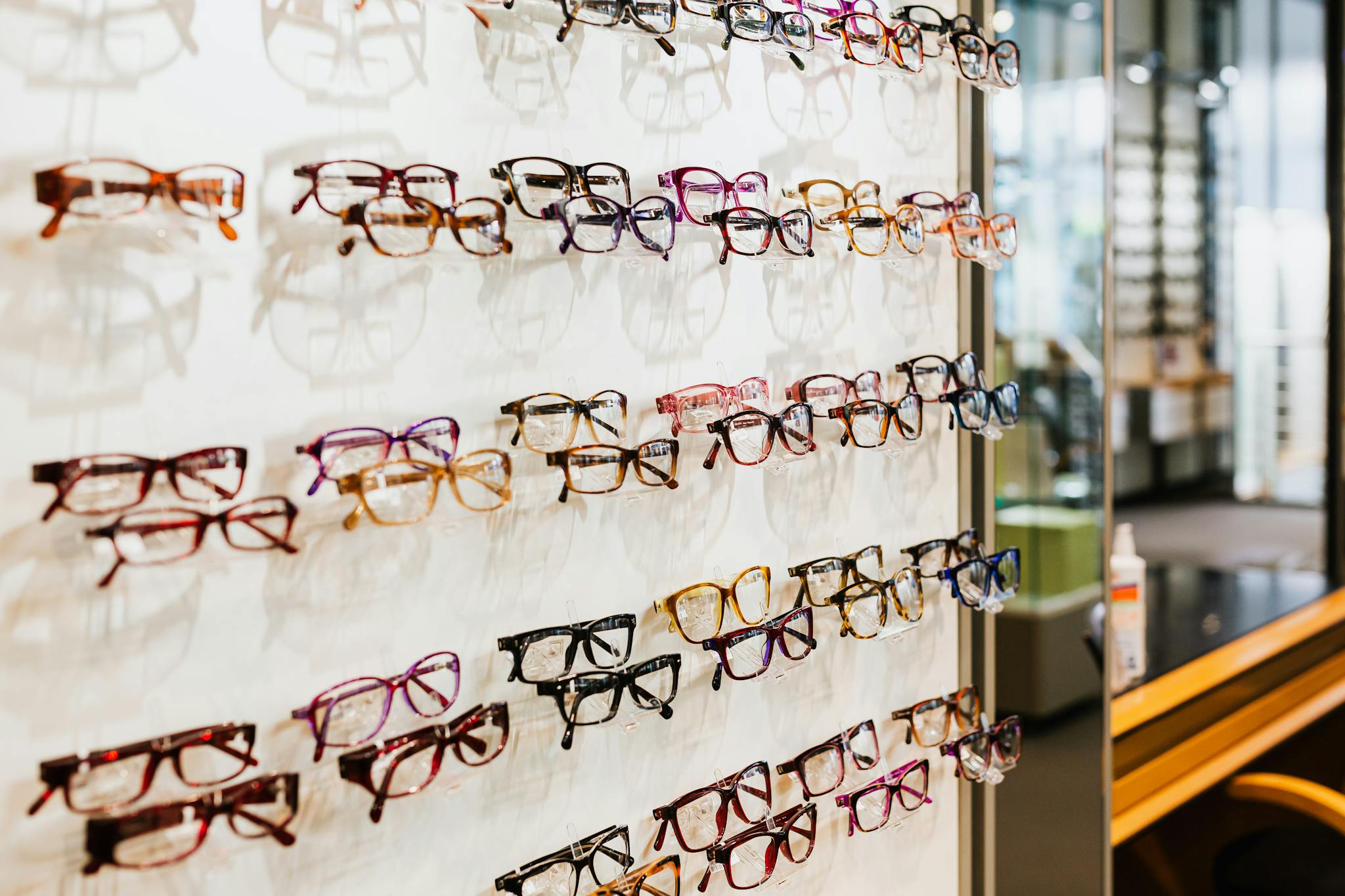 Colorful eyeglasses on display in a modern, well-lit eyewear store.