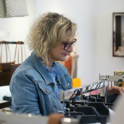 Elderly woman exploring fashion items in a boutique store, showcasing style and independence.