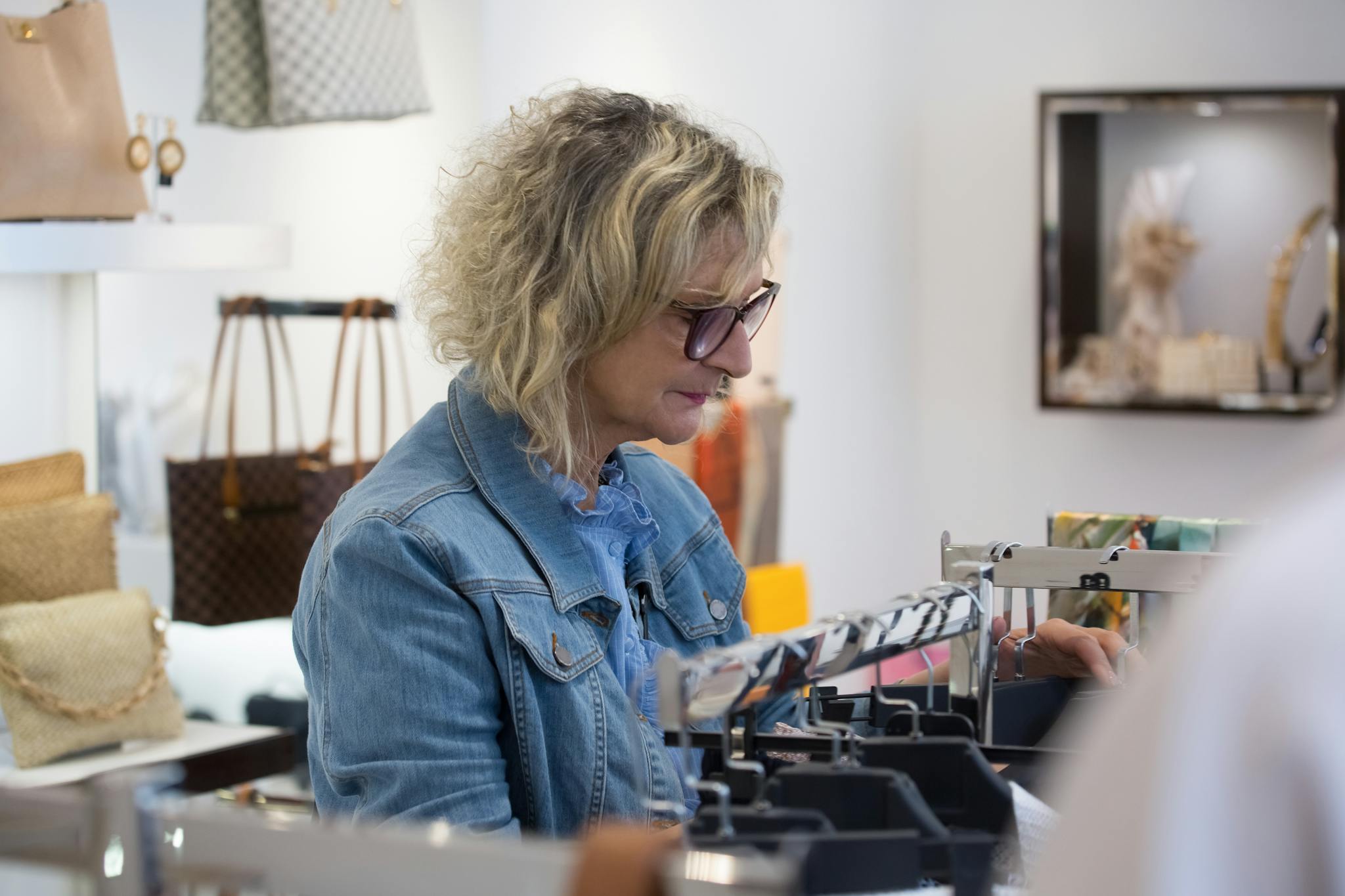 Elderly woman exploring fashion items in a boutique store, showcasing style and independence.